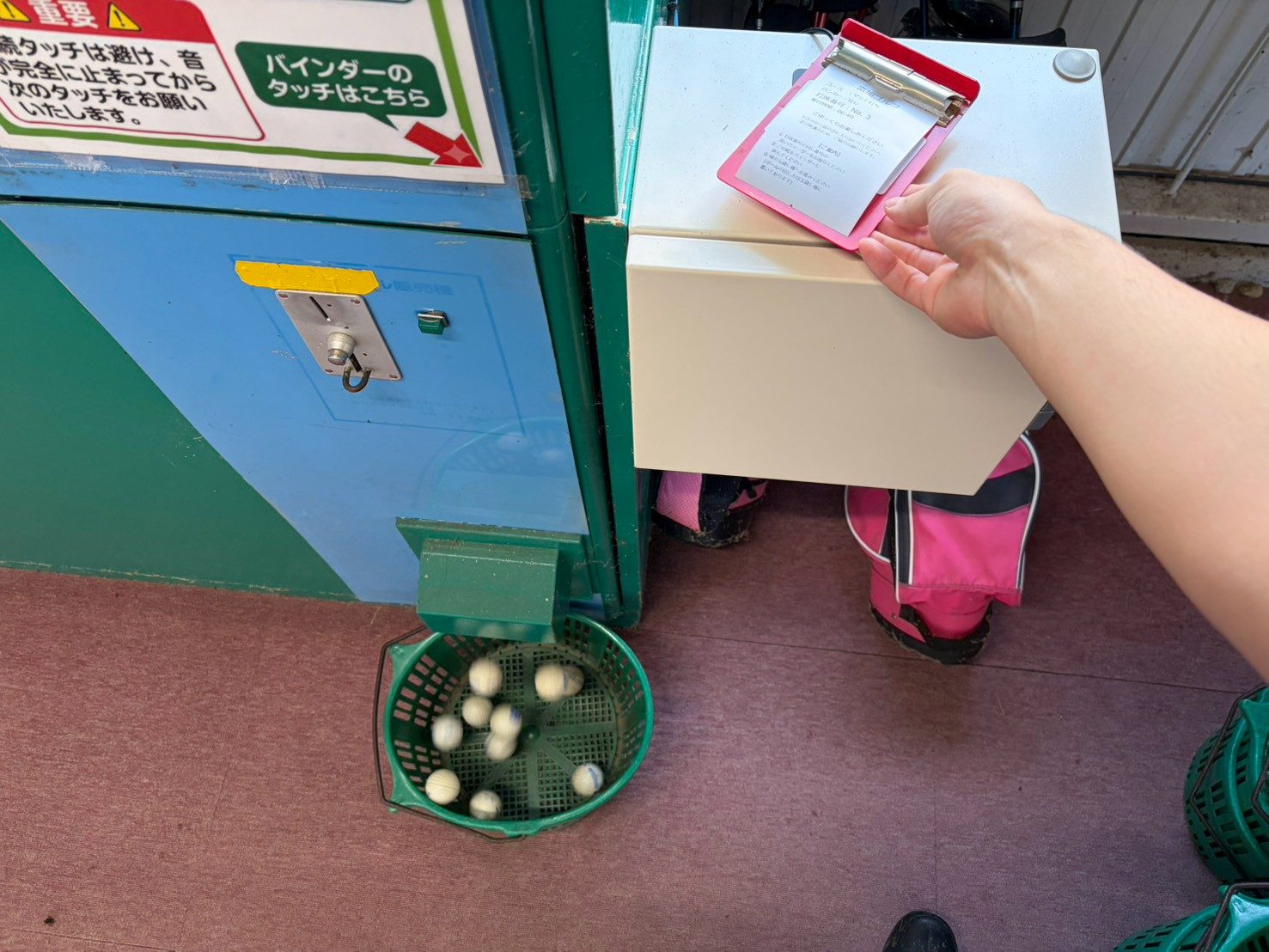 ボールを出す機械の「バインダーのタッチはこちら」と書かれた所にバインダーをかざすと、下のカゴにボールが出てくる様子