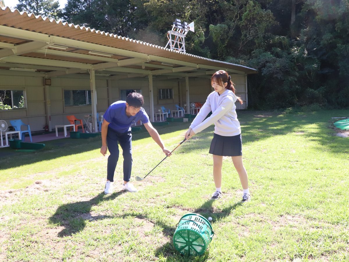 芝の上でスタッフがクラブの握り方を教えている様子