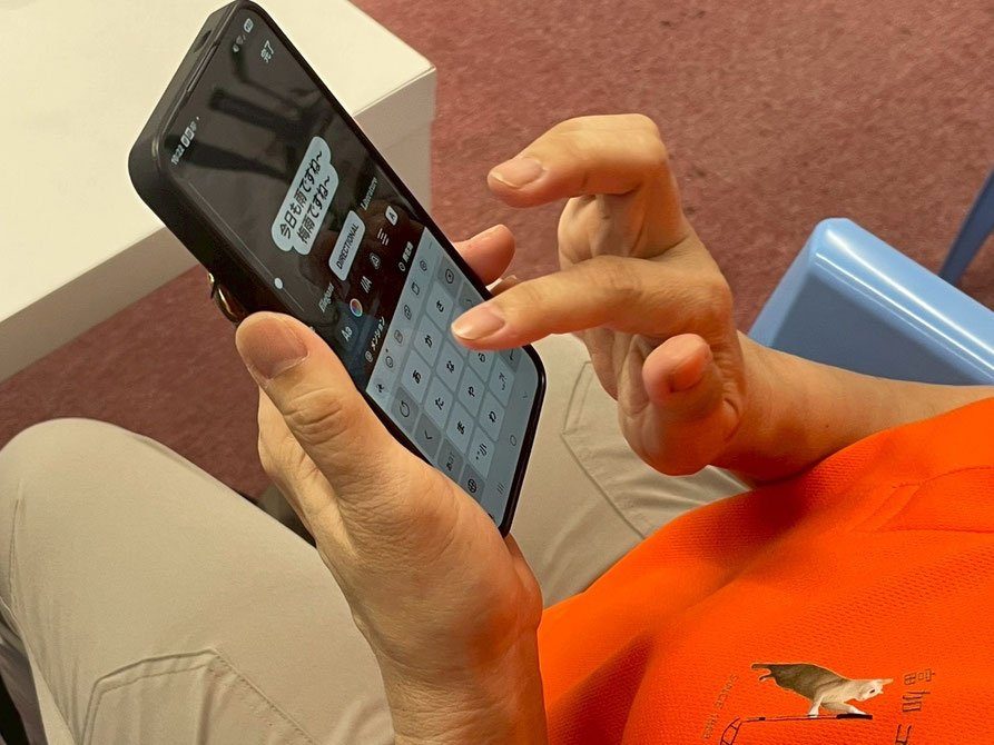 スマホでSNSの投稿を作るスタッフ